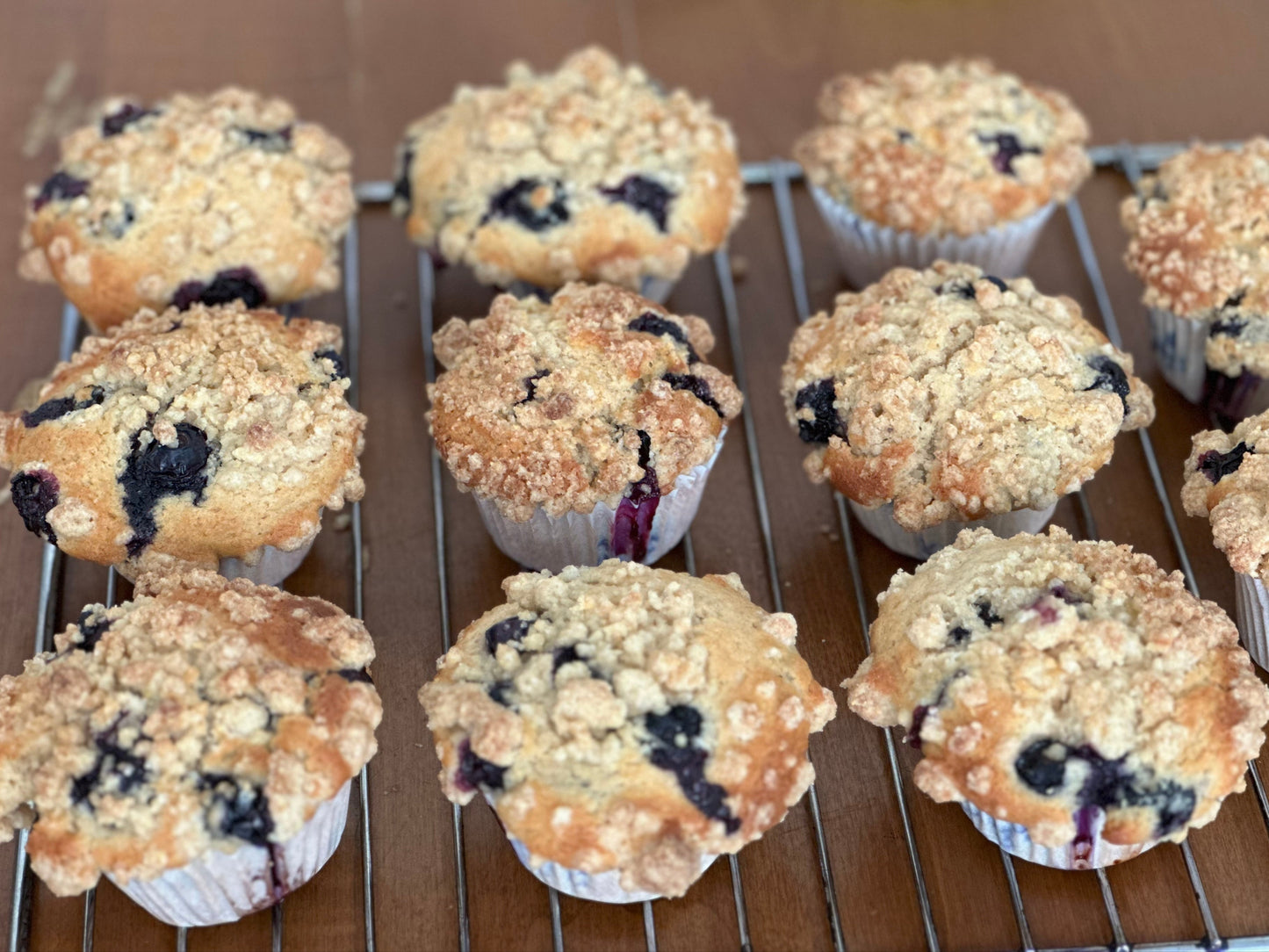 Blueberry muffins on a cooling rack with a brown background